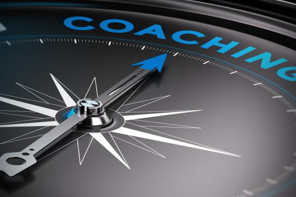 Attain personal goals, personal trainer concept. Conceptual Compass with needle pointing to the word coaching.